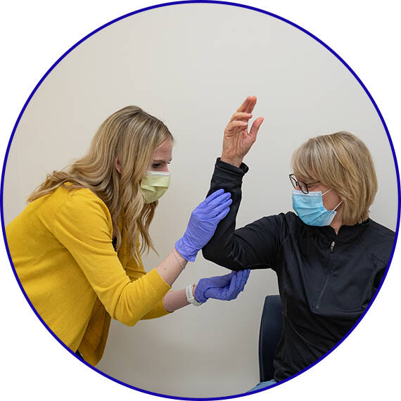 Student examining a Standardized Patient's right arm range of motion.
